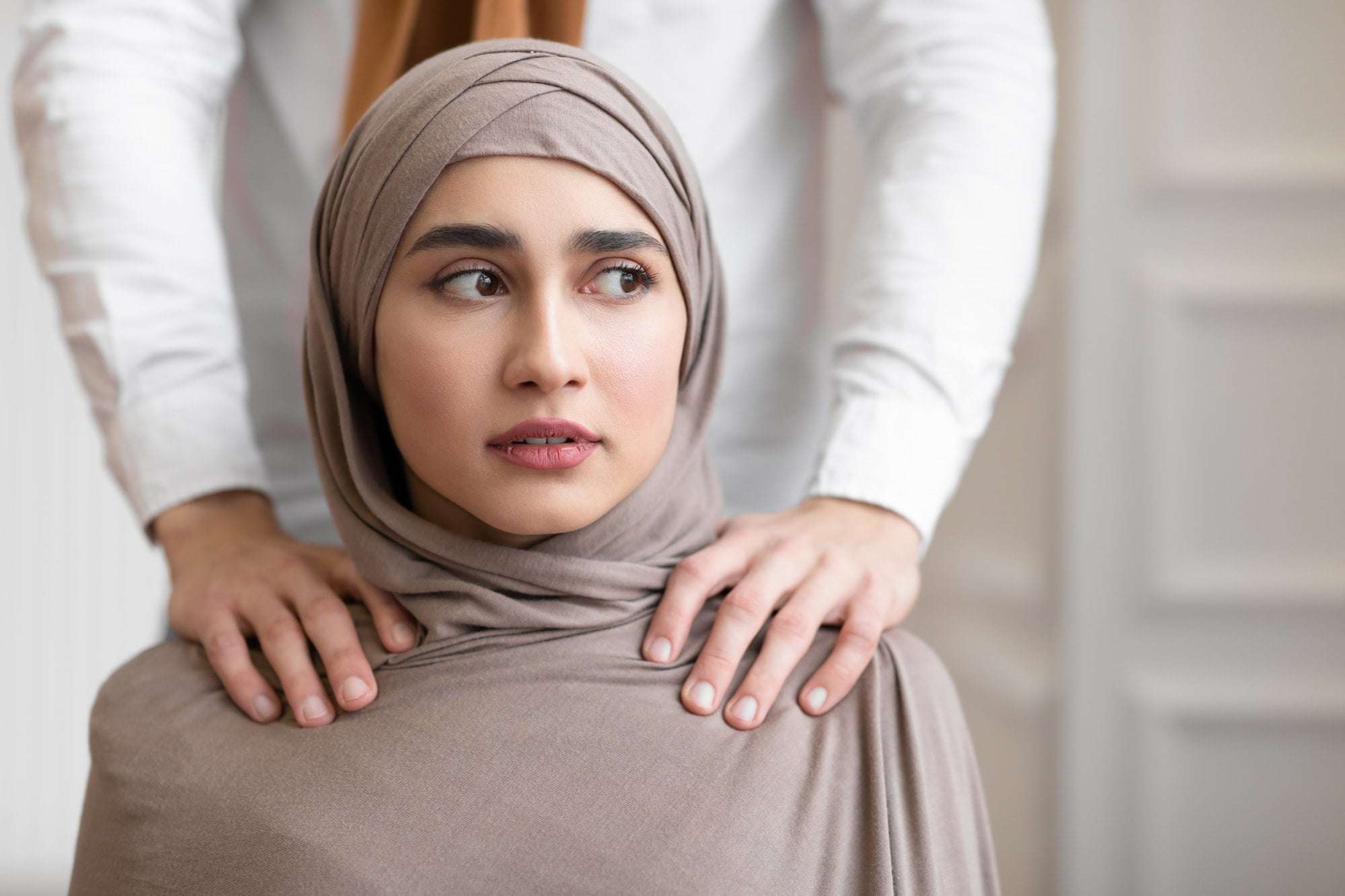 Domestic Violence, Muslim Husband Touching Shoulders Of Scared Wife Indoors