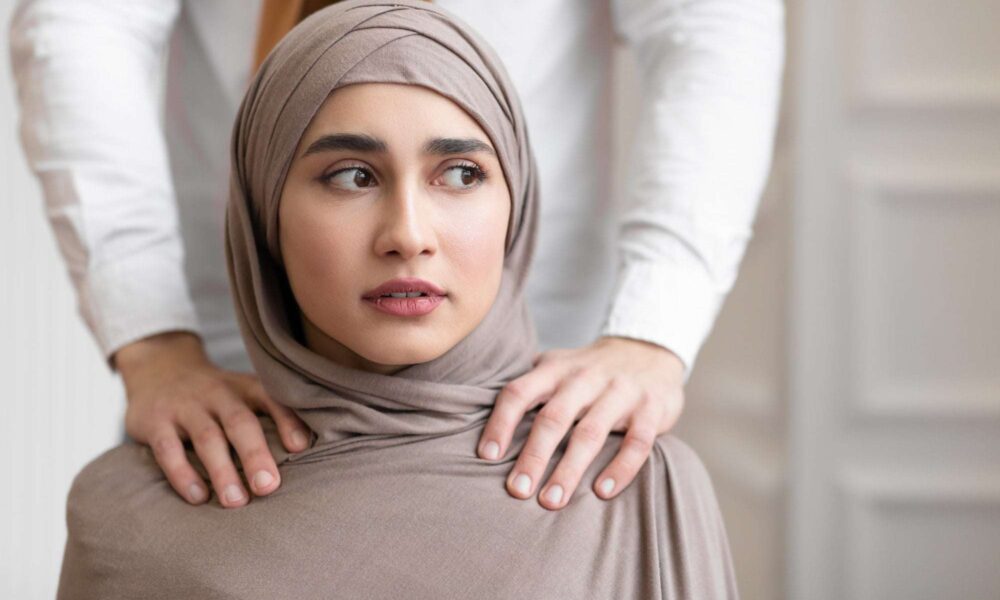 Domestic Violence, Muslim Husband Touching Shoulders Of Scared Wife Indoors